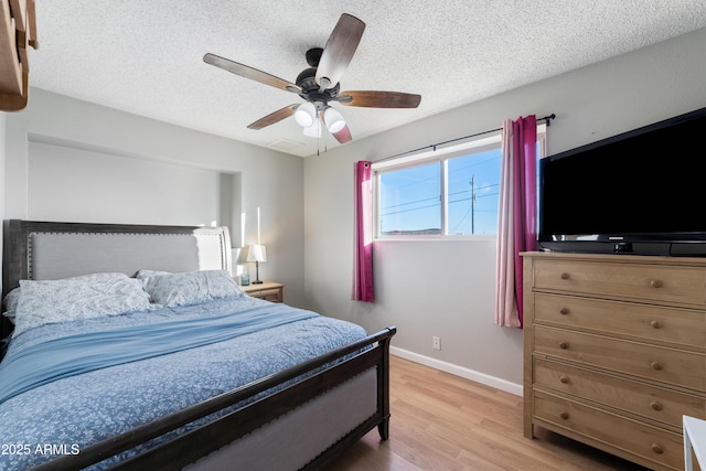 bedroom with light wood-style flooring, baseboards, a textured ceiling, and a ceiling fan