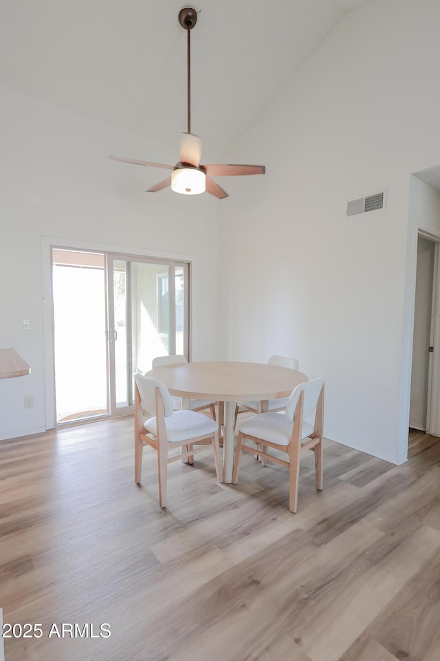 dining space with ceiling fan, high vaulted ceiling, and light hardwood / wood-style flooring