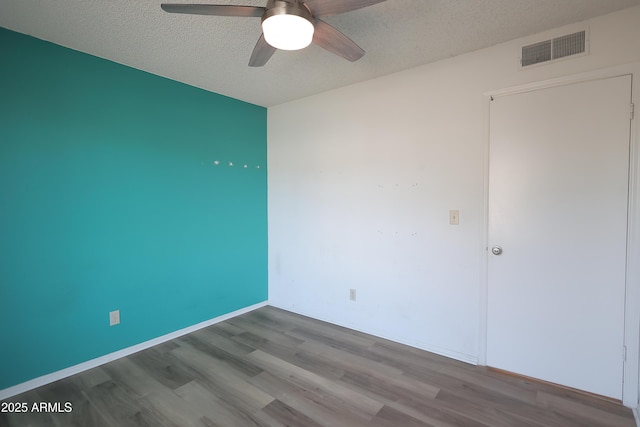 unfurnished room with ceiling fan, wood-type flooring, and a textured ceiling