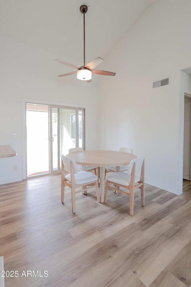 dining room featuring ceiling fan, high vaulted ceiling, and light wood-type flooring