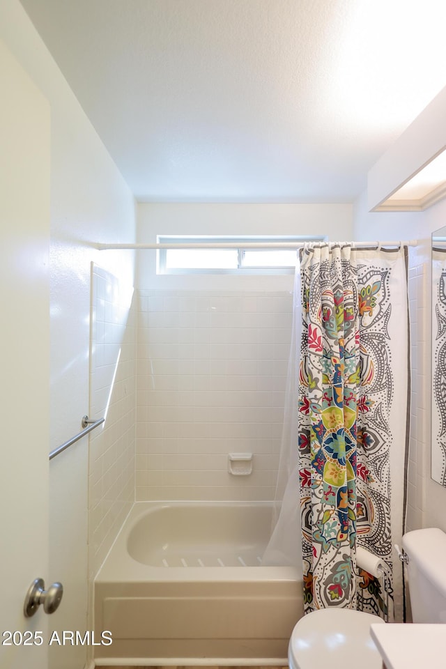 bathroom with shower / bathtub combination with curtain and toilet