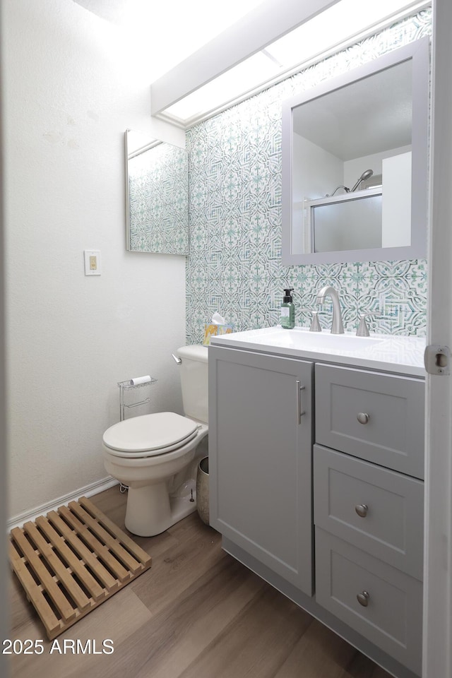 bathroom with vanity, hardwood / wood-style floors, a shower with door, and toilet