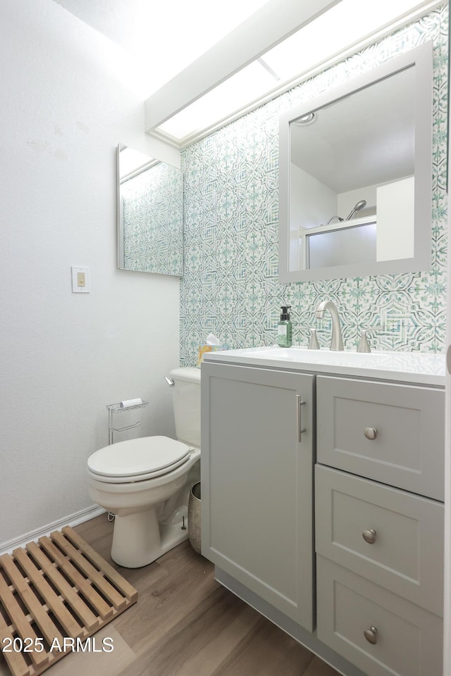 bathroom with vanity, wood-type flooring, a shower with door, and toilet