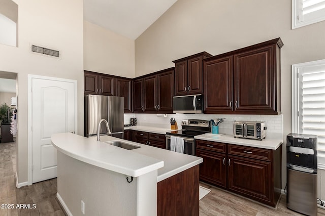 4137 E Stanford Ave, Gilbert, AZ 85234 - kitchen with appliances with stainless steel finishes, high vaulted ceiling, light wood-style flooring, light countertops, and decorative backsplash