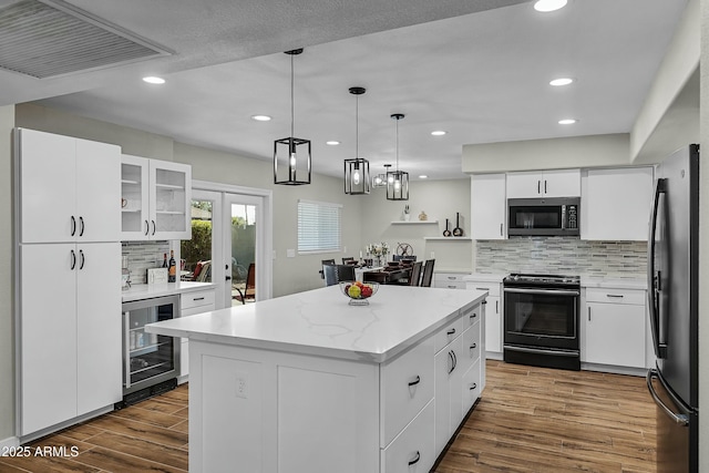 kitchen with white cabinets, black electric range oven, beverage cooler, and a kitchen island