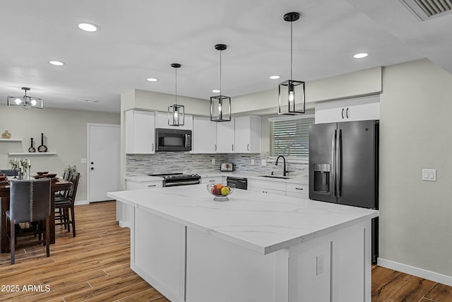 kitchen with a center island, white cabinets, sink, hanging light fixtures, and stainless steel appliances