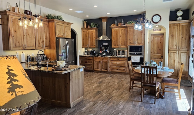 4990 N Pine Creek Canyon Dr, Pine, AZ 85544 - kitchen featuring stainless steel appliances, wall chimney range hood, arched walkways, dark wood-style flooring, and brown cabinets