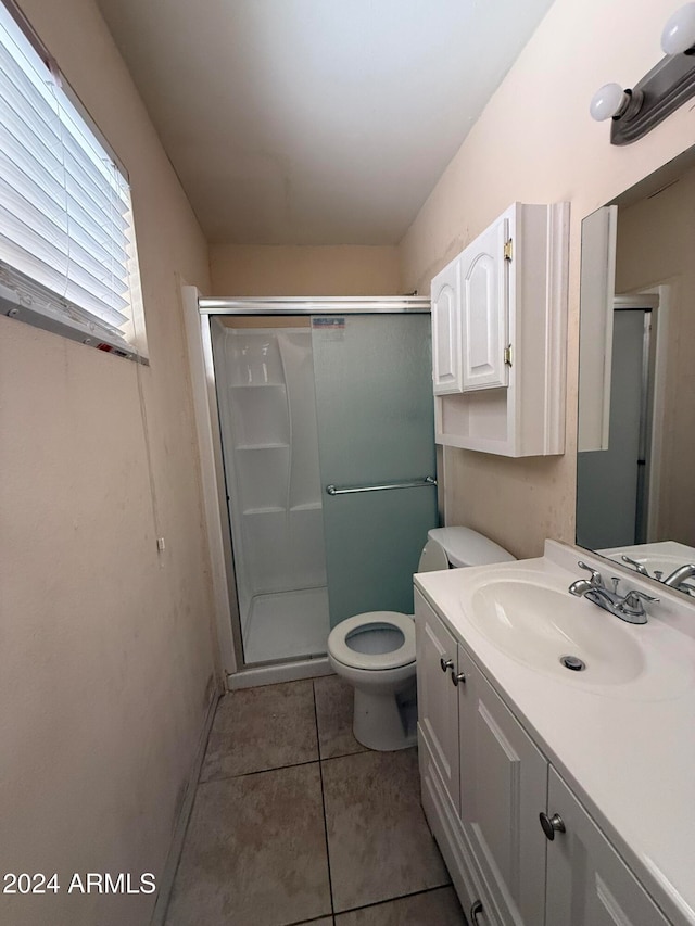 bathroom with toilet, vanity, tile patterned floors, and a shower with shower door