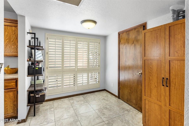 interior space with light tile patterned floors, visible vents, baseboards, and a textured ceiling