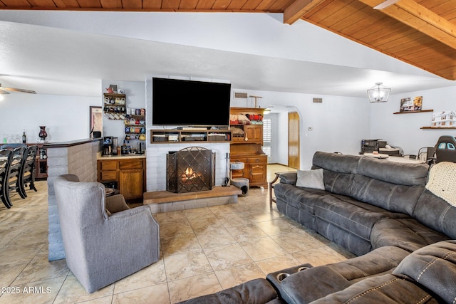 living area featuring lofted ceiling with beams, arched walkways, a fireplace, wood ceiling, and ceiling fan