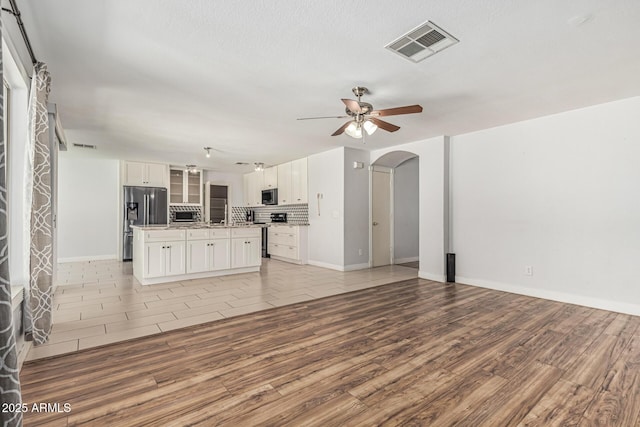 8939 W Villa Rita Dr, Peoria, AZ 85382 - unfurnished living room with light wood-style flooring, arched walkways, and a ceiling fan