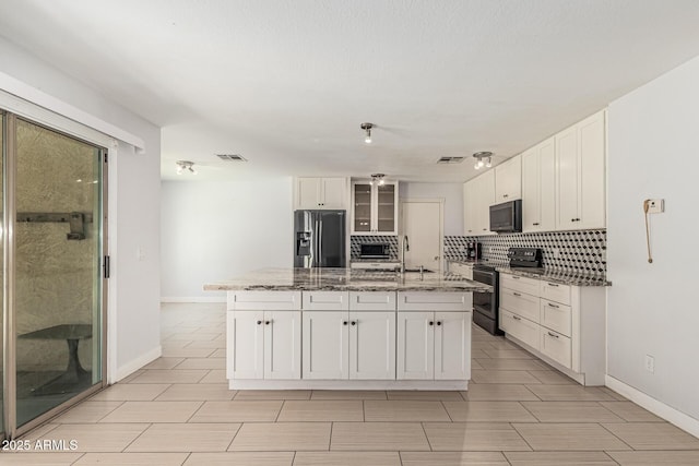 8939 W Villa Rita Dr, Peoria, AZ 85382 - kitchen with appliances with stainless steel finishes, white cabinets, a kitchen island with sink, light stone countertops, and glass insert cabinets