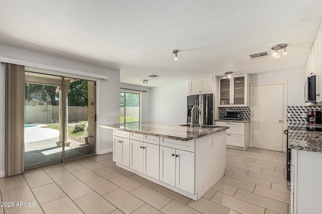 8939 W Villa Rita Dr, Peoria, AZ 85382 - kitchen featuring fridge with ice dispenser, stainless steel microwave, a kitchen island with sink, and tasteful backsplash