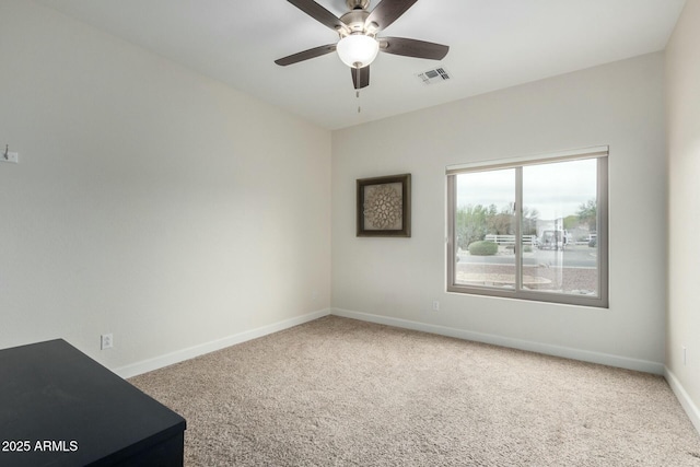 carpeted empty room with a ceiling fan, visible vents, and baseboards