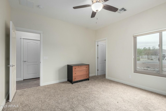 unfurnished bedroom with baseboards, visible vents, a ceiling fan, and light colored carpet