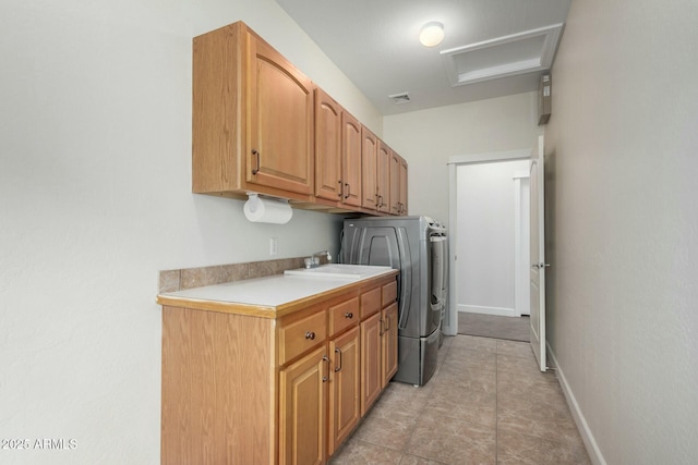 clothes washing area featuring washer / clothes dryer, cabinet space, attic access, a sink, and baseboards