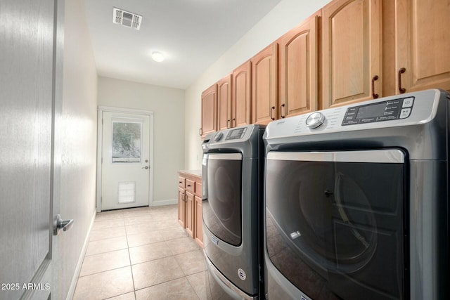 clothes washing area with light tile patterned floors, cabinet space, baseboards, visible vents, and washer and clothes dryer