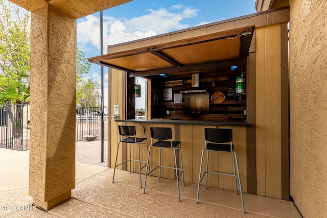 view of patio featuring exterior bar and fence