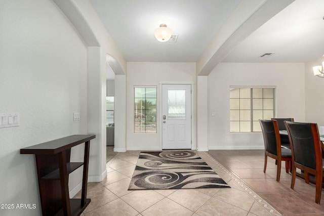 foyer entrance with arched walkways, visible vents, baseboards, and light tile patterned floors