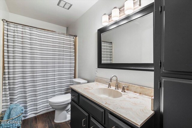 bathroom with a shower with curtain, vanity, hardwood / wood-style floors, and toilet