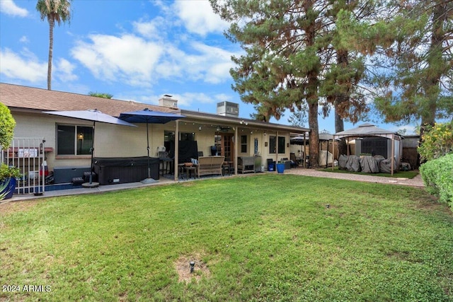 back of house with a gazebo, a lawn, and a hot tub