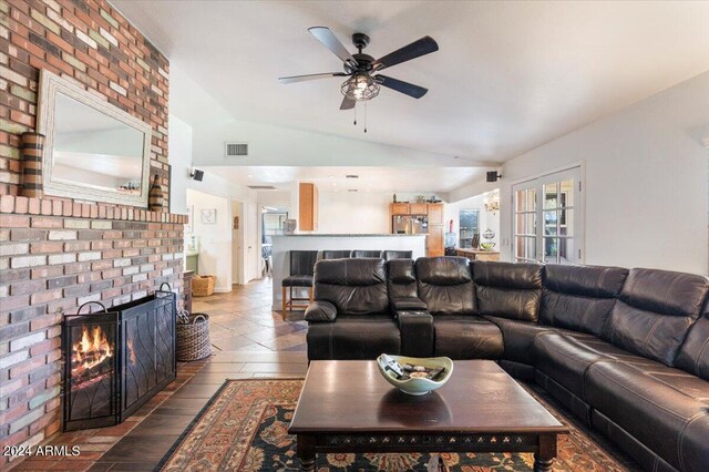 living room featuring lofted ceiling, a brick fireplace, and ceiling fan