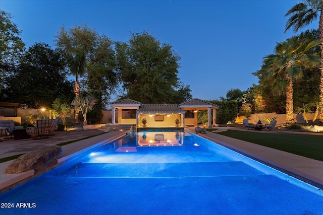 pool at dusk with a patio area and a jacuzzi