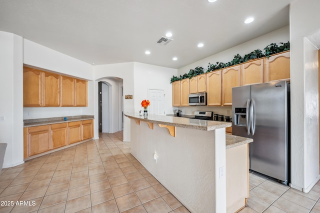 4414 W Monte Way, Laveen, AZ 85339 - kitchen featuring appliances with stainless steel finishes, arched walkways, light tile patterned flooring, recessed lighting, and a breakfast bar