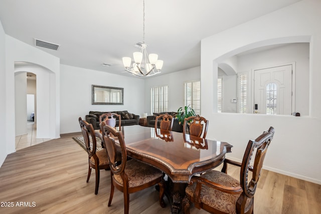 4414 W Monte Way, Laveen, AZ 85339 - dining space featuring arched walkways, a chandelier, light wood-style flooring, and baseboards
