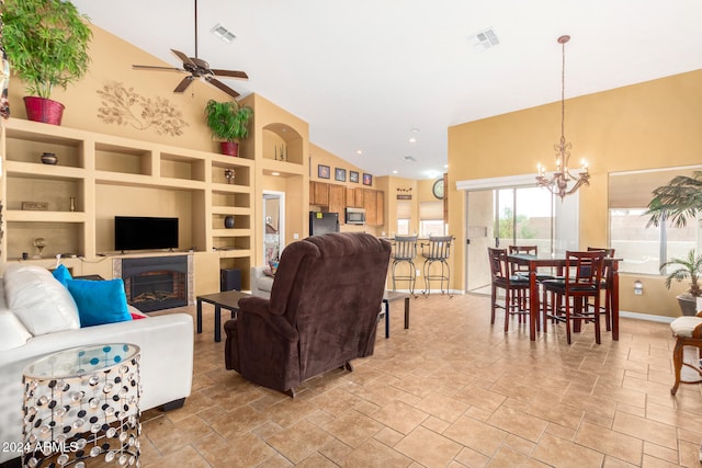 living room with built in shelves, high vaulted ceiling, and ceiling fan with notable chandelier