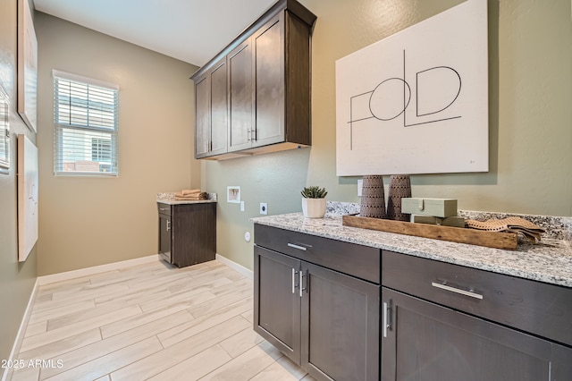 interior space featuring hookup for a washing machine, baseboards, hookup for an electric dryer, light wood-style flooring, and cabinet space