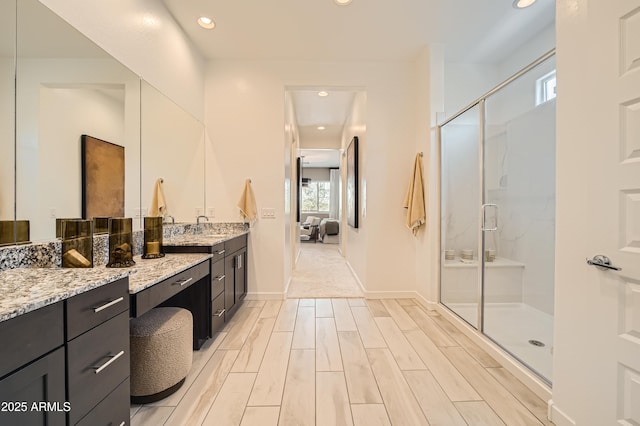 bathroom with connected bathroom, wood finish floors, recessed lighting, a stall shower, and vanity