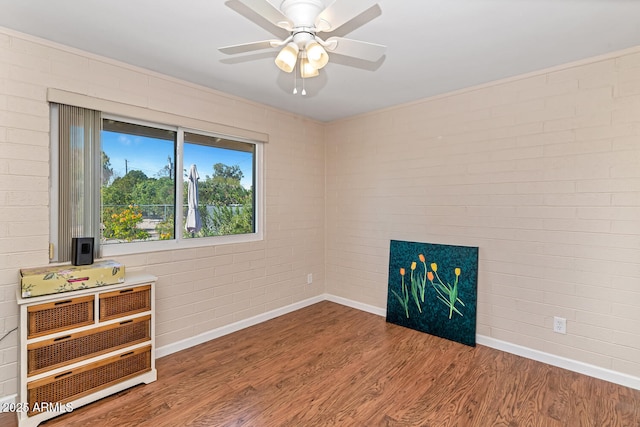 interior space featuring brick wall, a fireplace, wood finished floors, and baseboards