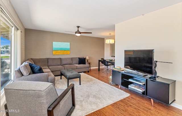 living area with ceiling fan, baseboards, and wood finished floors