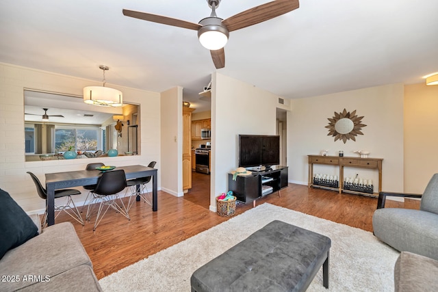 living area featuring wood finished floors, a ceiling fan, and baseboards