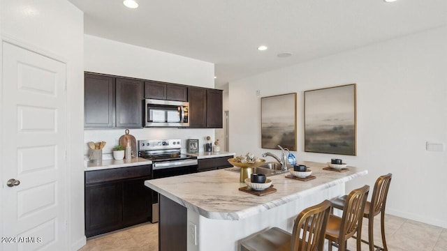 11890 E Cliffrose Ln, Florence, AZ 85132 - kitchen featuring stainless steel appliances, light countertops, a breakfast bar, recessed lighting, and light tile patterned floors