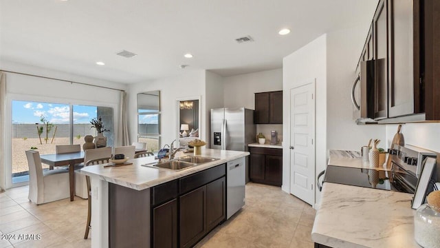 11890 E Cliffrose Ln, Florence, AZ 85132 - kitchen with appliances with stainless steel finishes, a sink, dark brown cabinets, a center island with sink, and light countertops