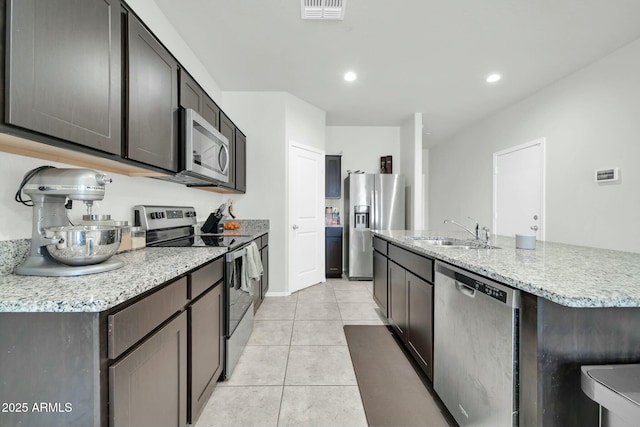 kitchen featuring visible vents, a center island with sink, light tile patterned floors, stainless steel appliances, and a sink