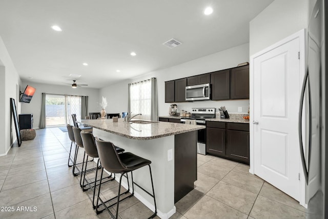 kitchen featuring a sink, light stone counters, a kitchen bar, and stainless steel appliances