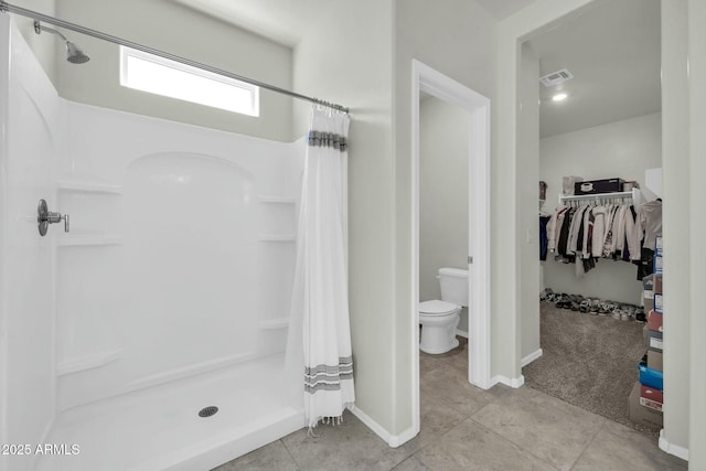 bathroom with tile patterned floors, visible vents, toilet, a shower stall, and a spacious closet