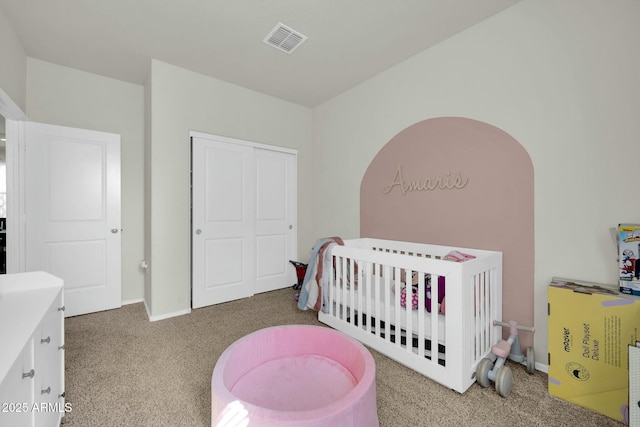 carpeted bedroom featuring baseboards, visible vents, a crib, and a closet