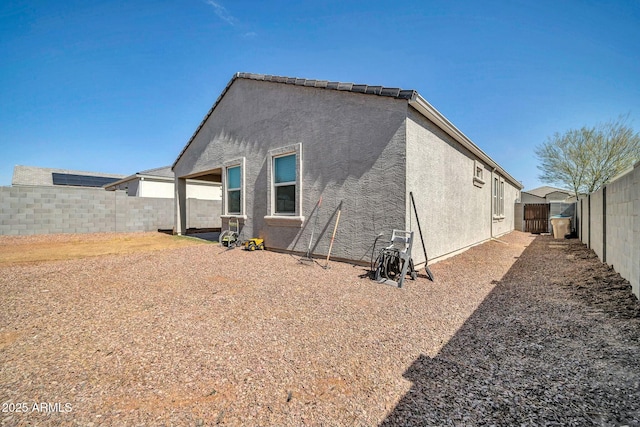 rear view of property with stucco siding and a fenced backyard