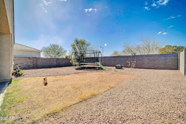 view of yard with a trampoline and a fenced backyard