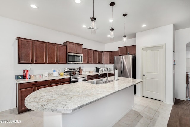 kitchen with hanging light fixtures, an island with sink, appliances with stainless steel finishes, and sink