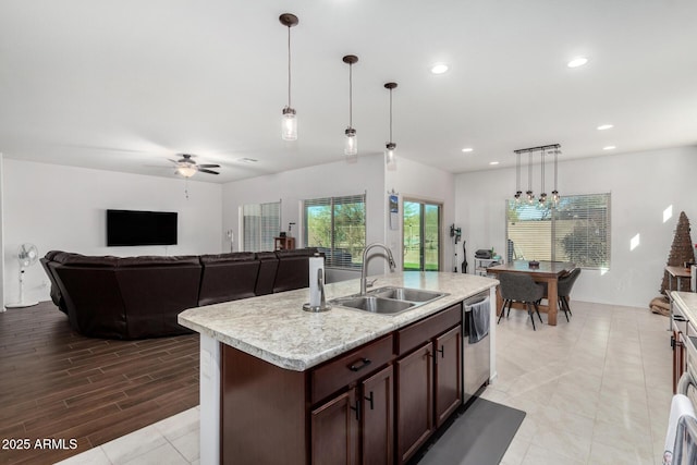 kitchen featuring an island with sink, decorative light fixtures, sink, and dark brown cabinets