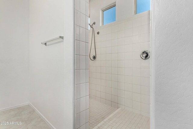 bathroom with a tile shower and tile patterned floors