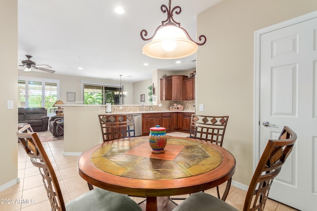 tiled dining room with ceiling fan with notable chandelier