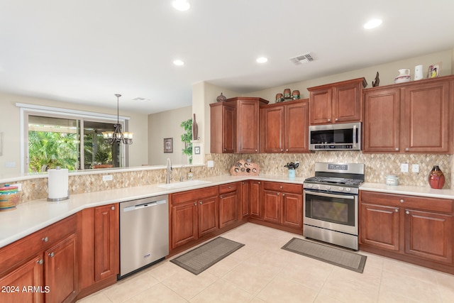 kitchen with an inviting chandelier, decorative light fixtures, light tile patterned floors, appliances with stainless steel finishes, and sink