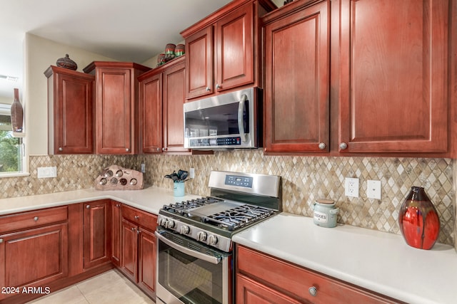 kitchen with light tile patterned floors, stainless steel appliances, and decorative backsplash