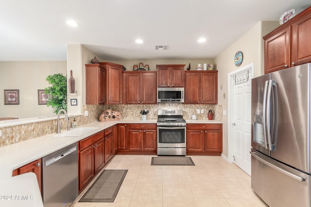 kitchen with appliances with stainless steel finishes, tasteful backsplash, light tile patterned floors, and sink